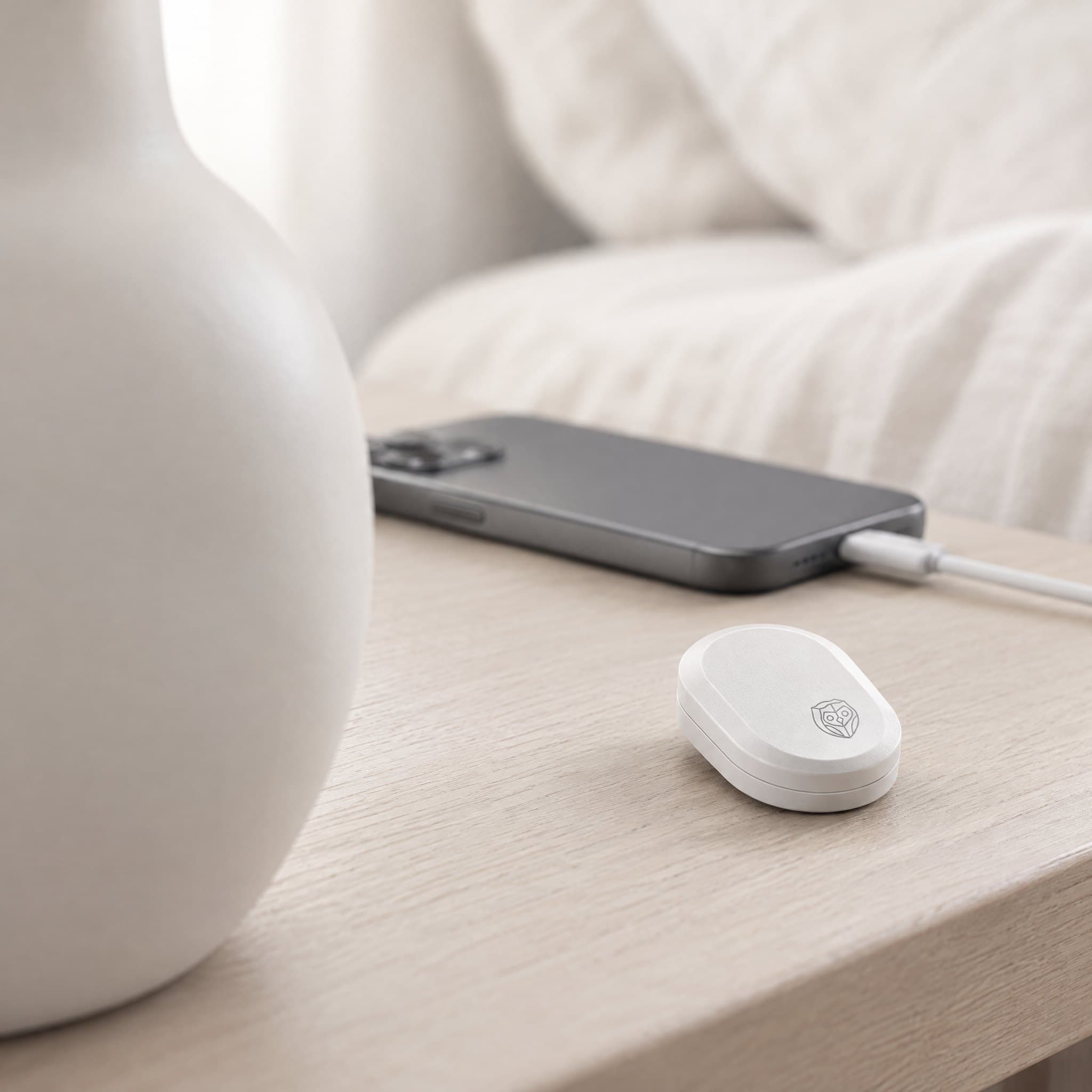 The sensor on a bedside table beside a phone lying face down on its charger